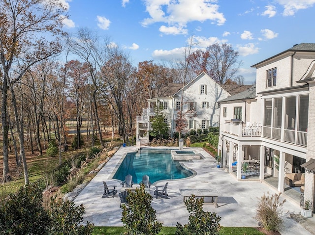 view of pool featuring a sunroom, a patio area, and an in ground hot tub