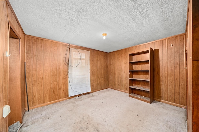 unfurnished bedroom with wooden walls and a textured ceiling