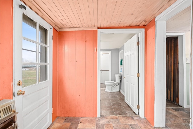 hall with ornamental molding, wooden walls, and wooden ceiling