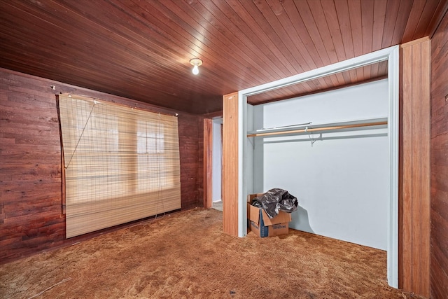 unfurnished bedroom with carpet flooring, a closet, wooden ceiling, and wood walls