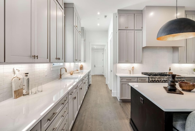 kitchen with gray cabinets, sink, decorative light fixtures, and light hardwood / wood-style flooring