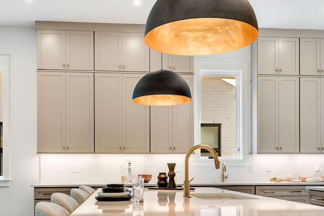 kitchen featuring tasteful backsplash, gray cabinetry, light stone countertops, and sink