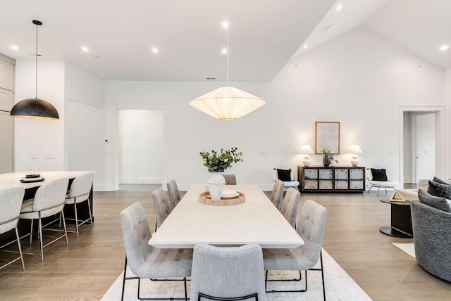 dining space featuring a high ceiling and light hardwood / wood-style flooring