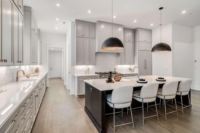 kitchen featuring hardwood / wood-style flooring, a large island, a kitchen breakfast bar, and sink