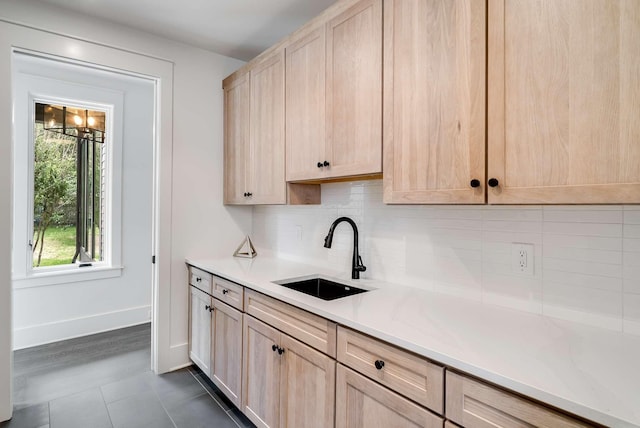 kitchen with tasteful backsplash, sink, dark tile patterned floors, and light brown cabinets