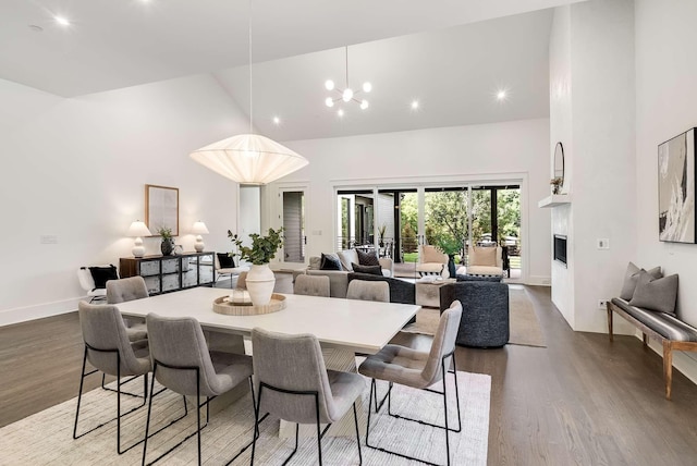 dining space featuring hardwood / wood-style floors, an inviting chandelier, and high vaulted ceiling