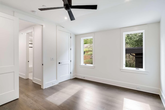 unfurnished bedroom featuring multiple windows, vaulted ceiling, ceiling fan, and dark wood-type flooring