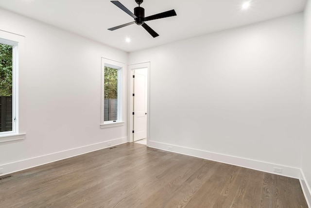 empty room featuring dark wood-type flooring, ceiling fan, and a healthy amount of sunlight