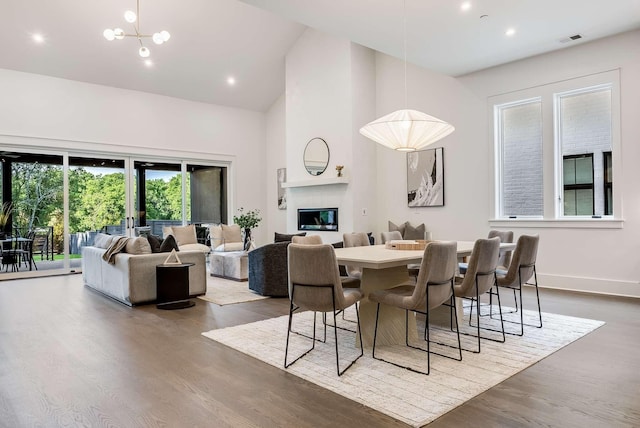 dining area featuring hardwood / wood-style flooring, a notable chandelier, and a high ceiling