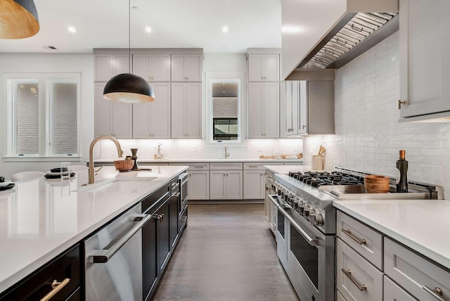 kitchen featuring appliances with stainless steel finishes, custom range hood, sink, decorative light fixtures, and gray cabinets