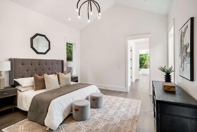 bedroom with a chandelier, hardwood / wood-style floors, and high vaulted ceiling