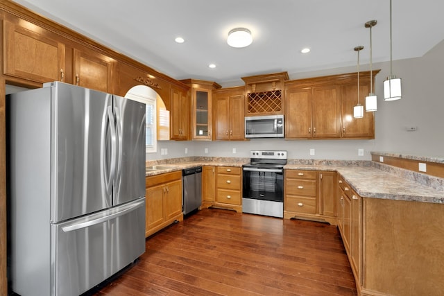 kitchen with appliances with stainless steel finishes, dark hardwood / wood-style flooring, decorative light fixtures, and light stone counters