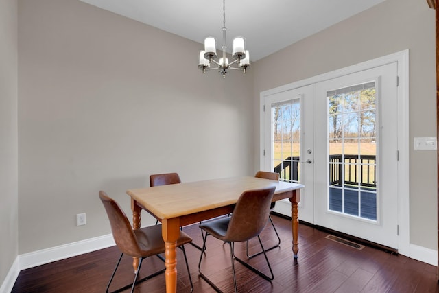 dining area with a notable chandelier, dark hardwood / wood-style floors, and french doors