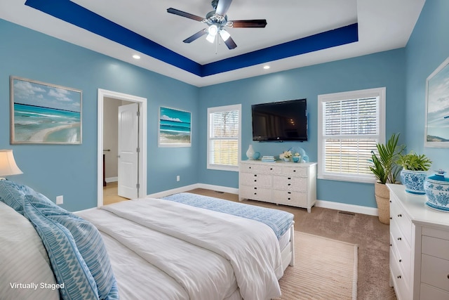 carpeted bedroom featuring a tray ceiling and ceiling fan