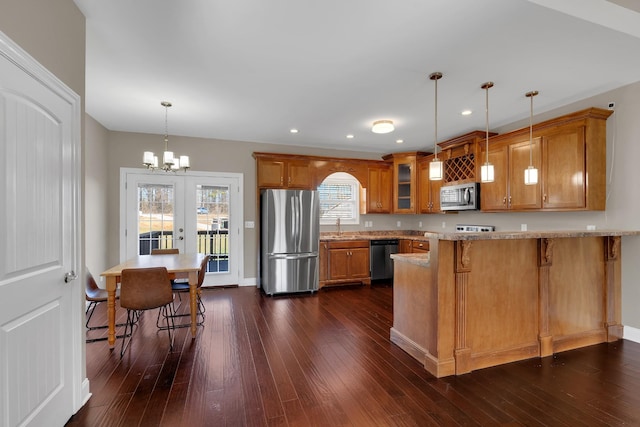 kitchen featuring sink, stainless steel appliances, kitchen peninsula, decorative light fixtures, and a breakfast bar area