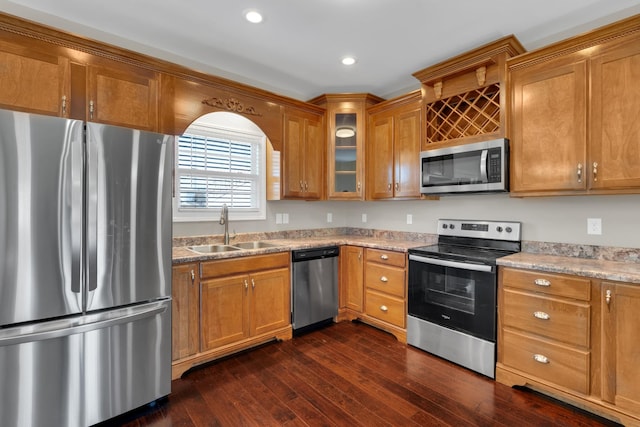 kitchen with light stone counters, dark hardwood / wood-style flooring, sink, and appliances with stainless steel finishes