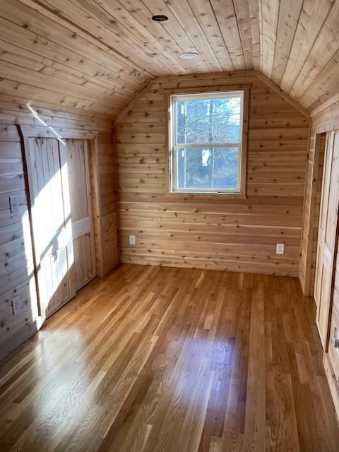 bonus room featuring lofted ceiling, wooden ceiling, and wood walls