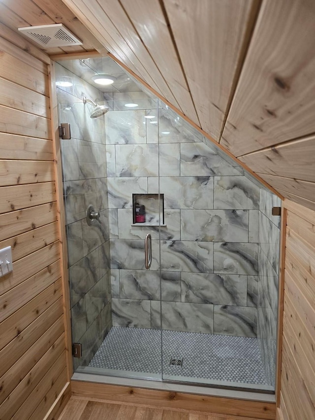 bathroom featuring wooden walls, hardwood / wood-style floors, and a shower with shower door