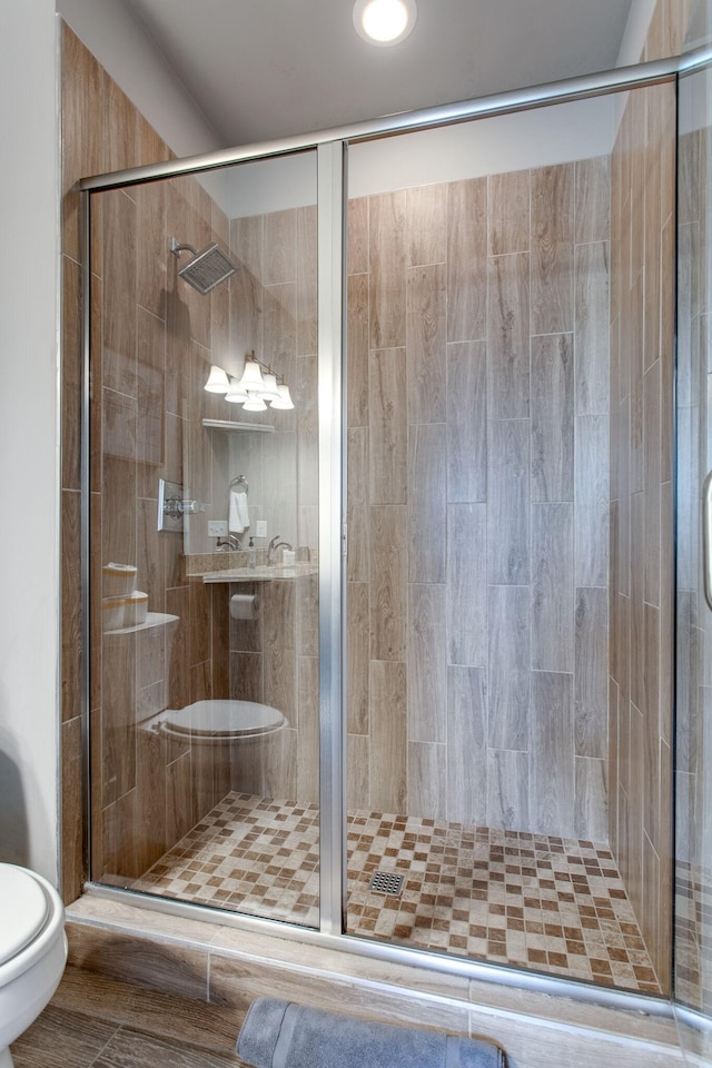 bathroom featuring toilet and a shower with door