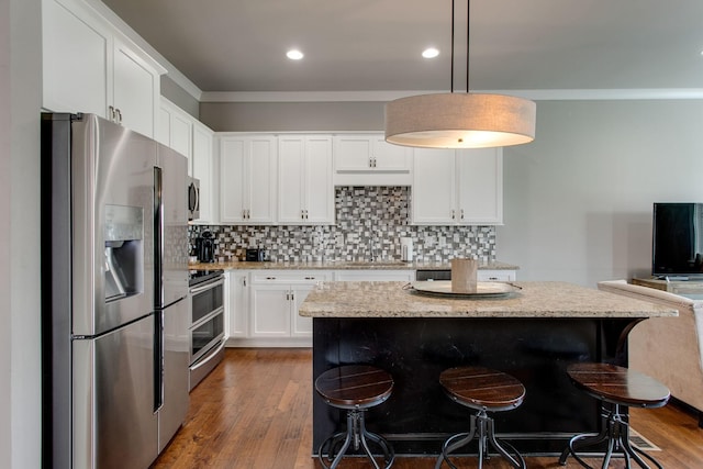 kitchen with a kitchen island, white cabinetry, stainless steel appliances, and hanging light fixtures