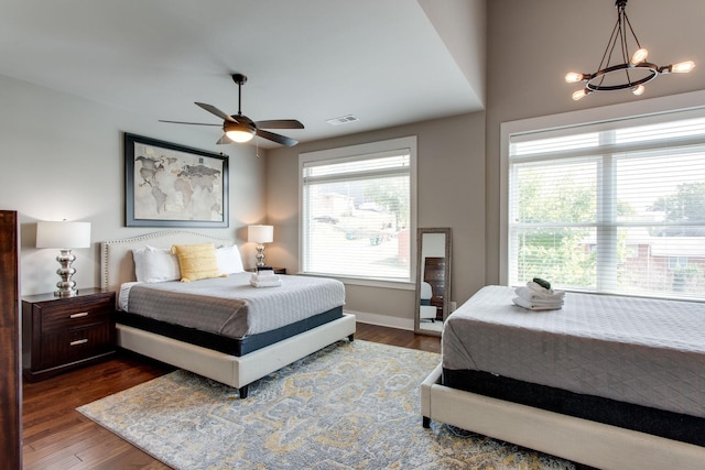 bedroom featuring dark hardwood / wood-style floors and ceiling fan with notable chandelier