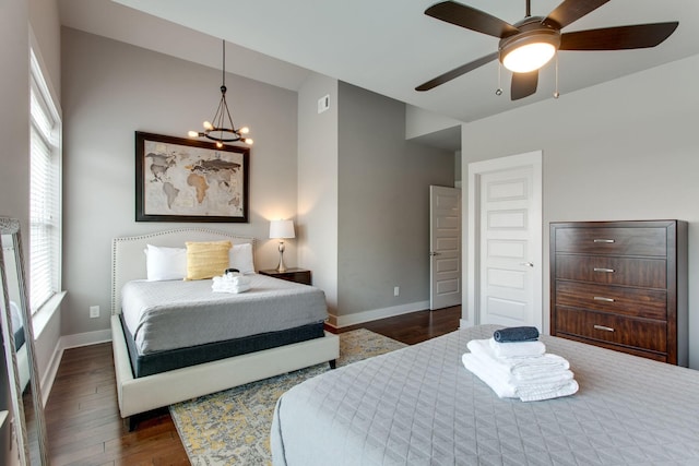 bedroom featuring ceiling fan with notable chandelier, dark hardwood / wood-style floors, and lofted ceiling