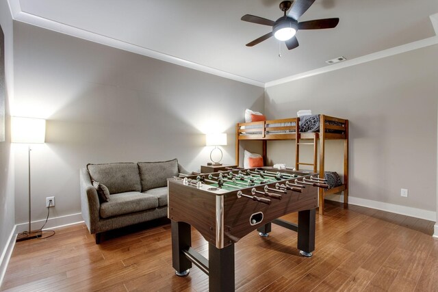 game room featuring hardwood / wood-style floors, ceiling fan, and crown molding