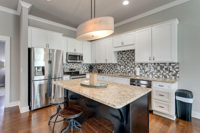 kitchen with pendant lighting, a center island, white cabinets, sink, and stainless steel appliances