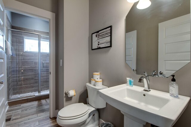 bathroom featuring toilet, hardwood / wood-style flooring, a shower with door, and sink