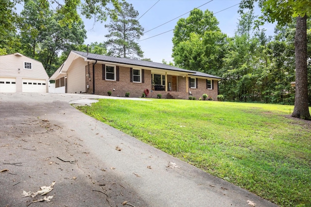 single story home featuring a garage, a front lawn, and an outdoor structure