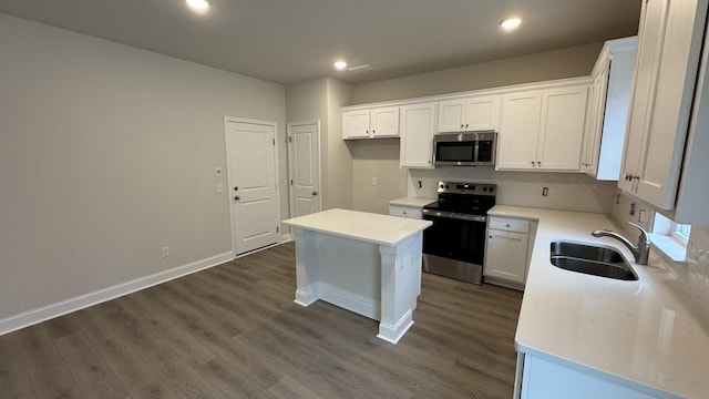 kitchen with a center island, dark wood-type flooring, sink, appliances with stainless steel finishes, and white cabinetry