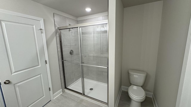 bathroom with tile patterned flooring, toilet, and an enclosed shower