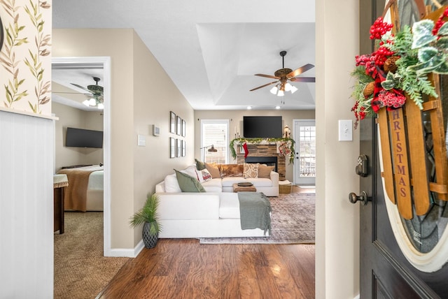 living room featuring a stone fireplace, ceiling fan, and dark hardwood / wood-style flooring