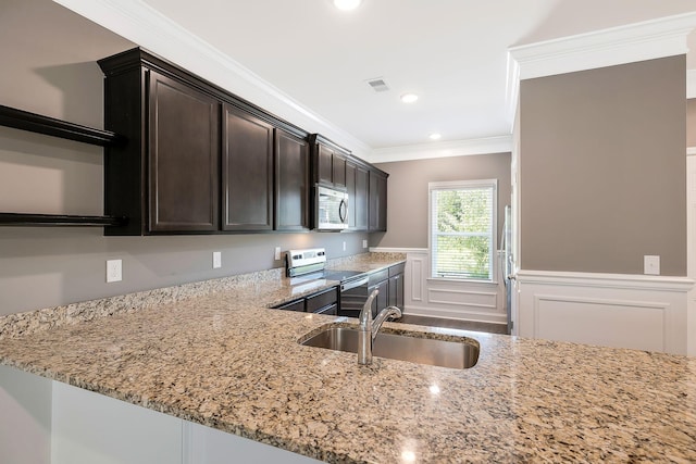 kitchen featuring sink, light stone countertops, ornamental molding, appliances with stainless steel finishes, and dark brown cabinetry