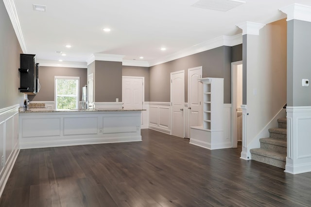 kitchen with kitchen peninsula, dark wood-type flooring, light stone counters, and crown molding