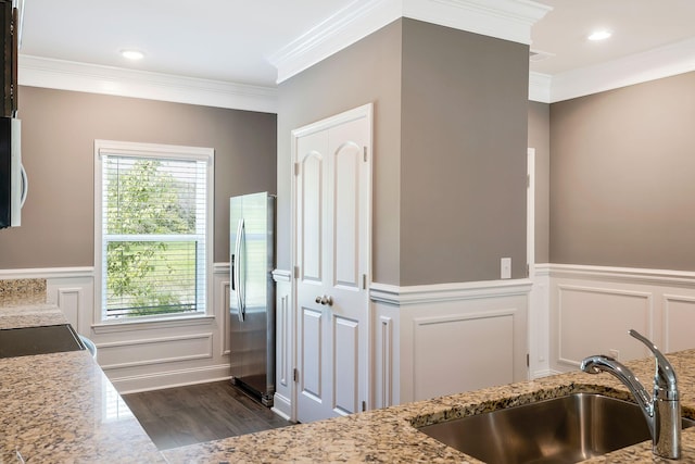 kitchen featuring plenty of natural light, sink, light stone countertops, and stainless steel refrigerator with ice dispenser