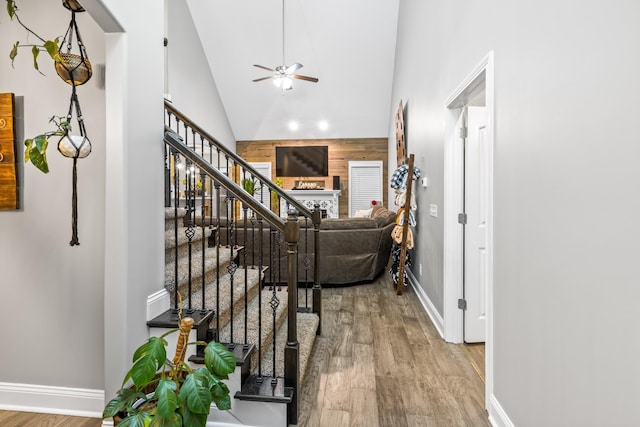 corridor with light hardwood / wood-style flooring, high vaulted ceiling, and wooden walls