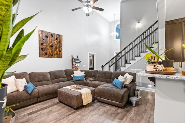 living room featuring ceiling fan with notable chandelier, hardwood / wood-style flooring, and high vaulted ceiling