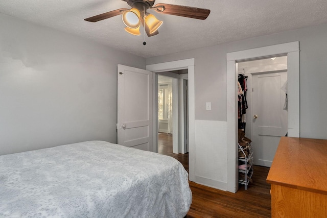 bedroom with a textured ceiling, dark hardwood / wood-style floors, a closet, and ceiling fan