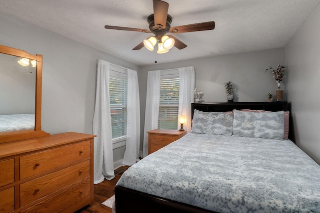 bedroom featuring ceiling fan, dark hardwood / wood-style flooring, and a textured ceiling