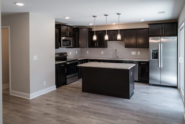 kitchen featuring sink, a center island, pendant lighting, appliances with stainless steel finishes, and light wood-type flooring