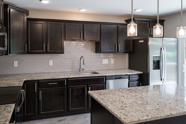 kitchen featuring decorative backsplash, stainless steel appliances, sink, a center island, and hanging light fixtures