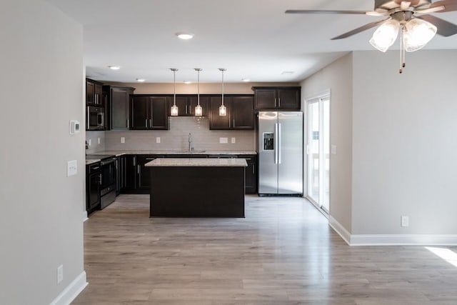 kitchen featuring sink, hanging light fixtures, decorative backsplash, a kitchen island, and appliances with stainless steel finishes