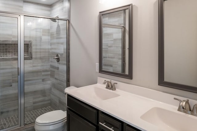 bathroom featuring a shower with door, vanity, and toilet