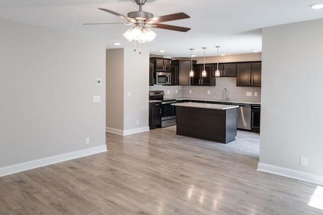 kitchen featuring decorative backsplash, appliances with stainless steel finishes, sink, decorative light fixtures, and a kitchen island