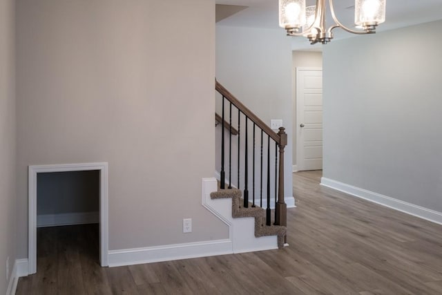 stairs featuring hardwood / wood-style floors and an inviting chandelier