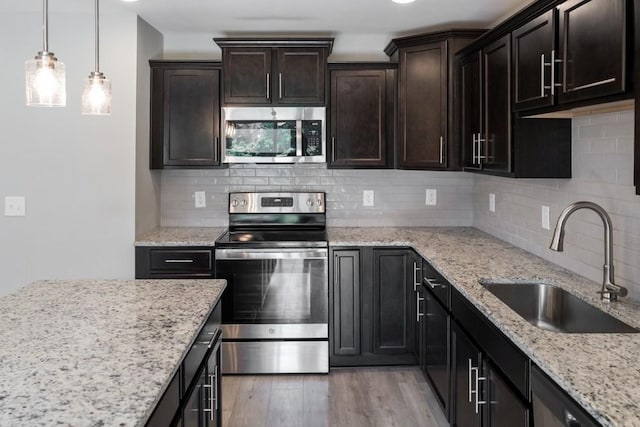 kitchen featuring appliances with stainless steel finishes, backsplash, dark brown cabinetry, sink, and light hardwood / wood-style floors