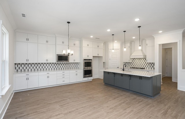 kitchen with a spacious island, decorative backsplash, hanging light fixtures, appliances with stainless steel finishes, and white cabinets