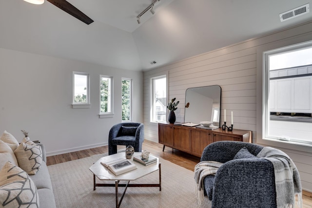 living room with vaulted ceiling, rail lighting, and light wood-type flooring