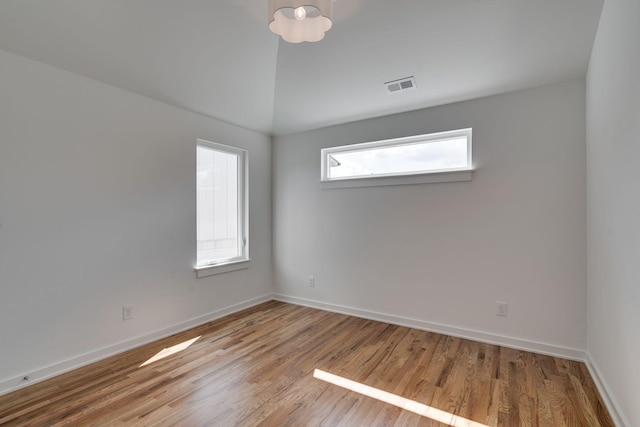 spare room with vaulted ceiling and light hardwood / wood-style flooring